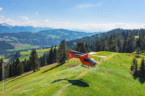 Wallpaper Mural Red rescue helicopter of the German Luftrettung landing on a green hilltop. Allgäu, Bavaria, Germany Torontodigital.ca