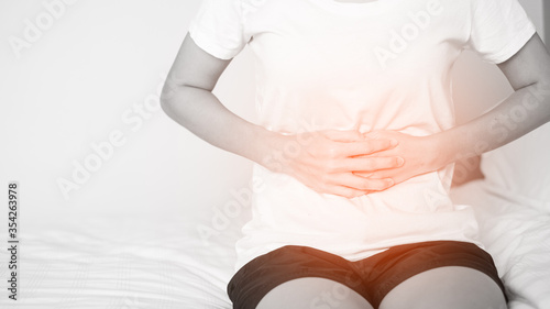 Wallpaper Mural Young woman suffering from abdominal pain while sitting on bed at home, Healthcare concept.. Torontodigital.ca