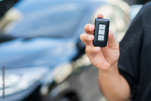 Man holding remote car key standing near his car. Young man getting new car with the car key.