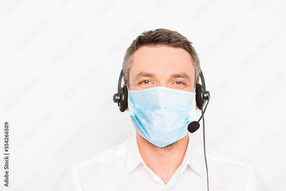 Portrait of mature man worker of call center assistance wear medical mask on face and headset with microphone help other people isolated on gray background, stop pandemic of corona virus concept Portrait of mature man worker of call center assistance wear medical mask on face and headset with microphone help other people isolated on gray background, stop pandemic of corona virus concept