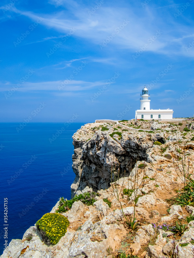 idyllic view to the cape cavalleria lighthouse in front of steep cliffs at the mediterranean sea nearby es mercadal, minorca