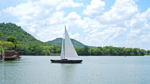 Yacht sailing in a lake and mountain background.