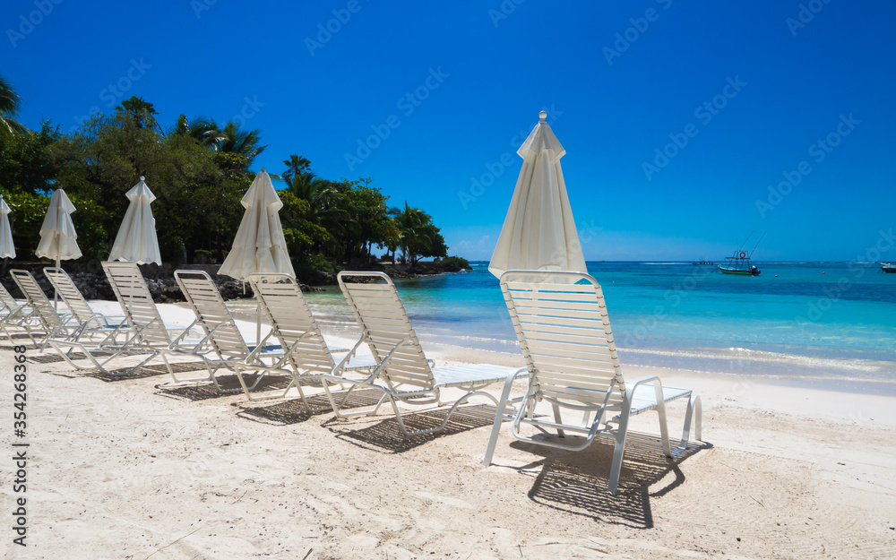 Naklejka premium a group of empty beach chairs inviting for a sunbath at a white beach in front of crystal clear water in the caribbean