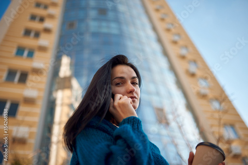 Pretty female communicating by phone on the city street
