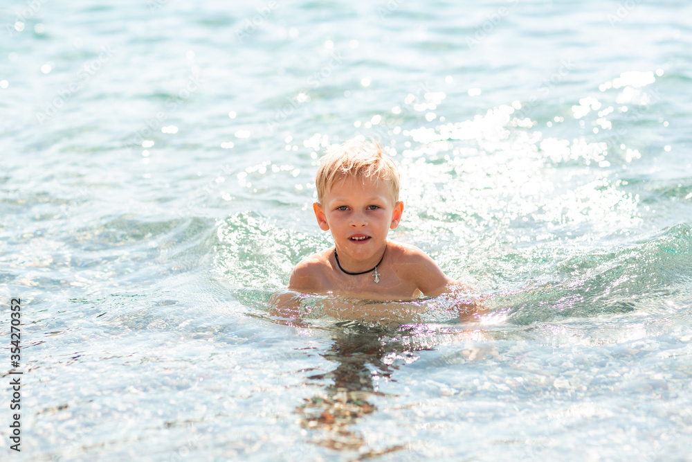 Happy little boy playing in the waves at the seaside