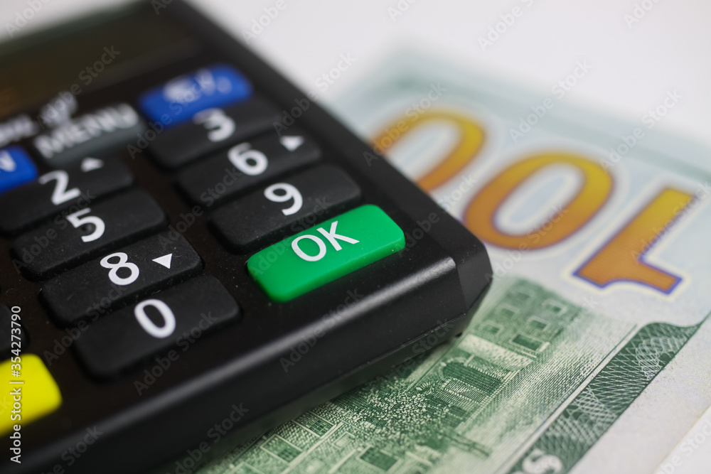 Bank transfer and account balance concept: Isolated calculator with 100 us dollar paper banknote, focus on green o.k. button Bank transfer and account balance concept: Isolated calculator with 100 us dollar paper banknote, focus on green o.k. button