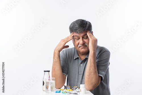 Senior man with mustache having a headache at home.