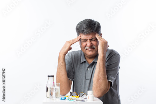 Senior man with mustache having a headache at home.