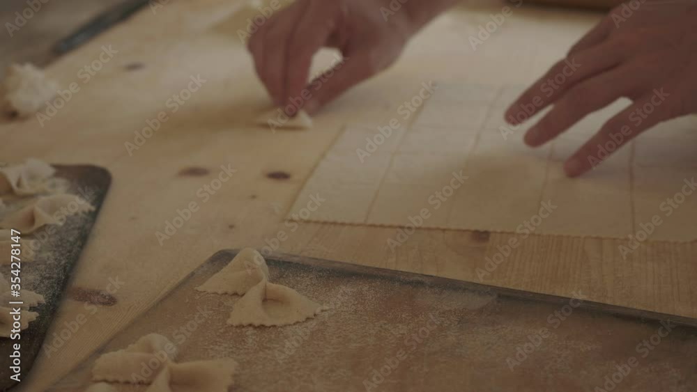 Close up process of homemade vegan farfalle pasta with durum wheat flour. The cook uses a rolling pin to stretch the dough, traditional Italian pasta - Woman cooks the food in the kitchen Close up process of homemade vegan farfalle pasta with durum wheat flour. The cook uses a rolling pin to stretch the dough, traditional Italian pasta - Woman cooks the food in the kitchen