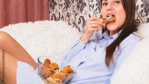 Young happy woman eating deep fried chicken, closeup. Woman eats chicken wings, calorie intake and health risks, cholesterol