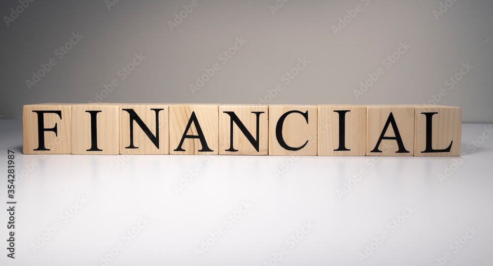 financial market concept - text FINANCIAL written on wooden blocks with downward stack of coins Close up. financial market concept - text FINANCIAL written on wooden blocks with downward stack of coins Close up.
