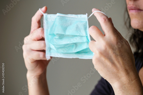 Woman putting on a protection mask to prevent from COVID-19 and other infections.