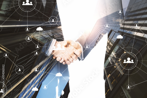 Businessmen shaking hands with network cloud hologram