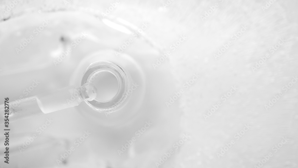 Close-up serum in glass bottle with water drops in ice background and selective focus, horizontal banner format. Concept summertime beauty product with copy space, top view. Cooling summer facial care Close-up serum in glass bottle with water drops in ice background and selective focus, horizontal banner format. Concept summertime beauty product with copy space, top view. Cooling summer facial care