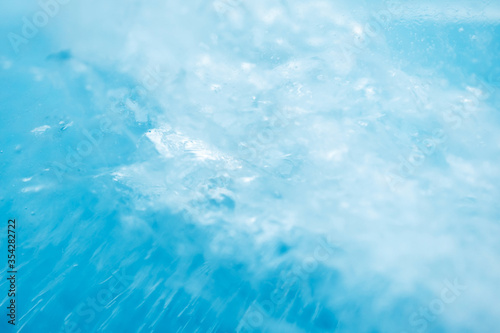 Macro ice texture with selective focus. Frosted water on blue background. Summer cold abstract defocused wallpaper