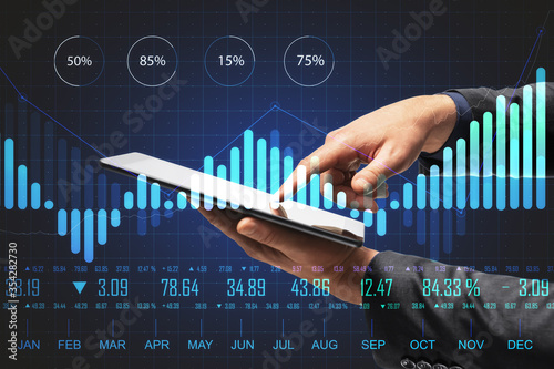 Hand using tablet on desktop with abstract forex chart hologram