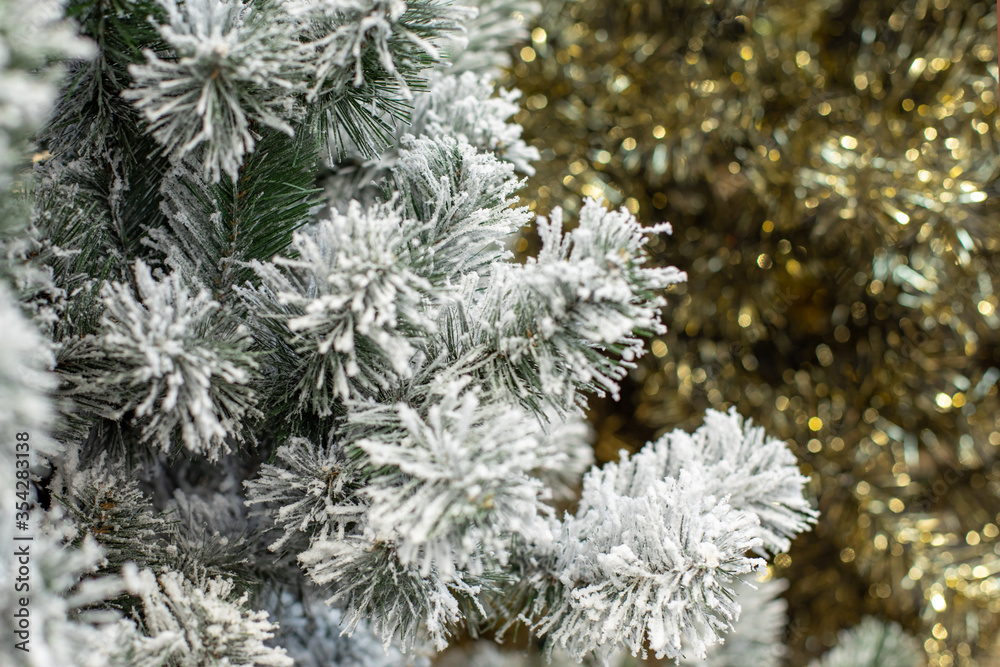 A branch of a fake Christmas tree in hoarfrost, snowy fir needles. Festive Christmas background for design.