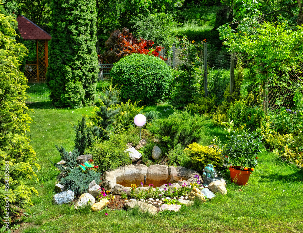 Naklejka premium flower garden and artesian fountain in the yard