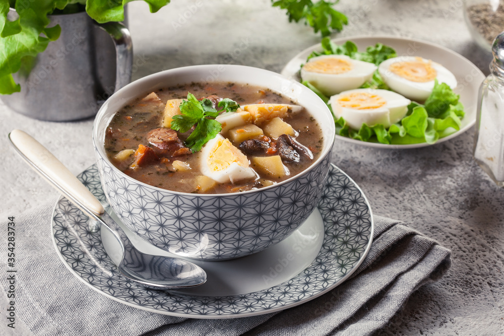 The sour soup made of rye flour with mushrooms served with eggs The sour soup made of rye flour with mushrooms served with eggs
