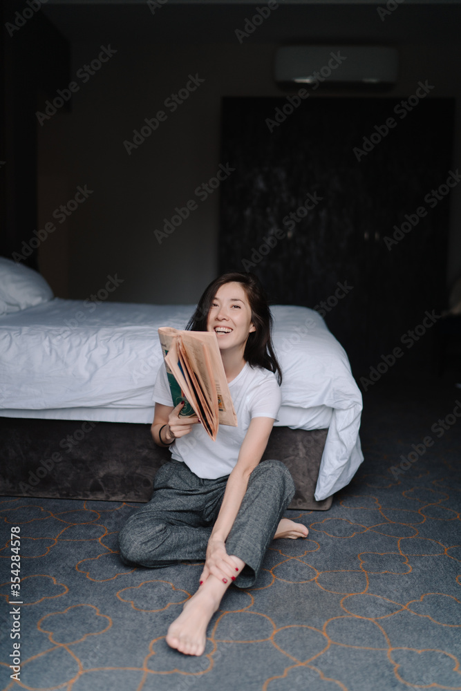 Young Female Sitting at Home and Reading Newspaper