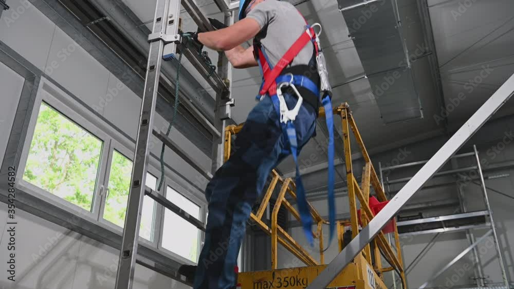 Air Duct Installer Coming Down Ladder From Scaffold In Safety Harness On. 