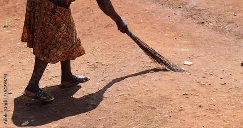 Woman sweeps the street with an old broom. Kenya, Africa
