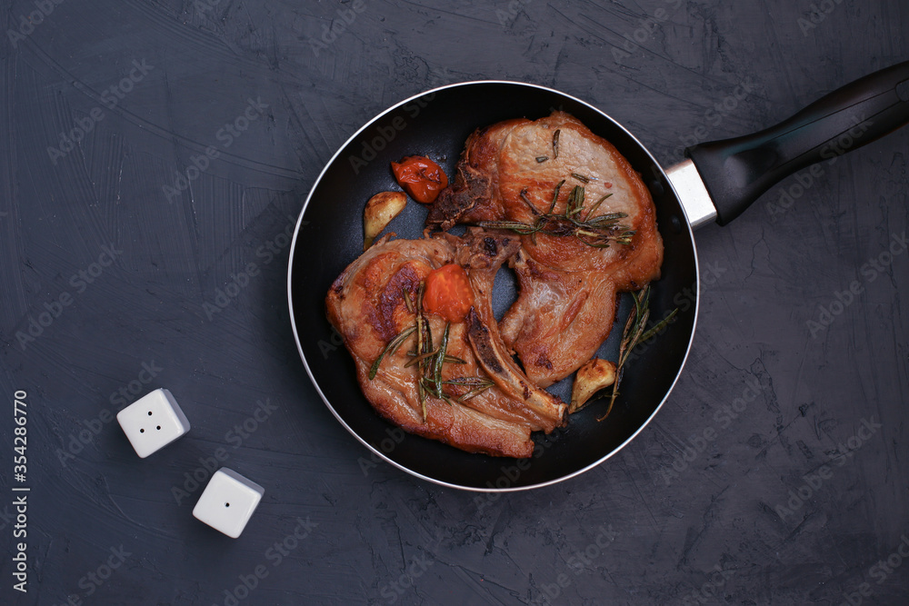 Roasted pork steak in frying pan on black background Roasted pork steak in frying pan on black background