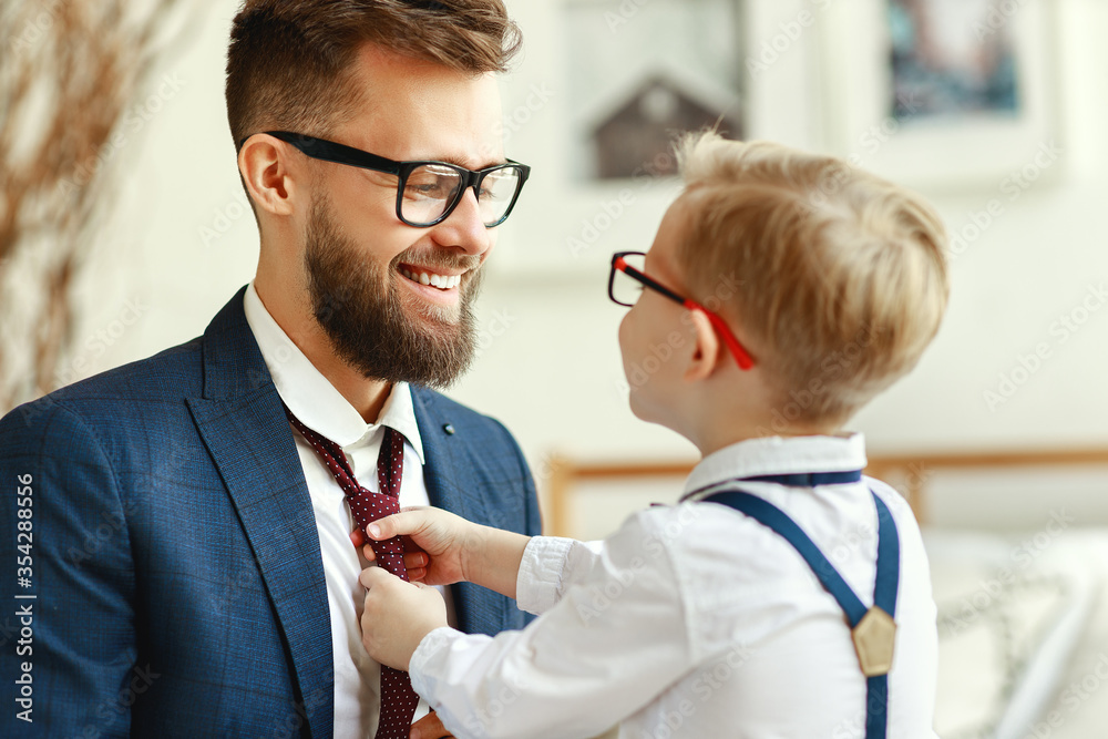 Fototapeta happy son helps father tie a necktie at home.