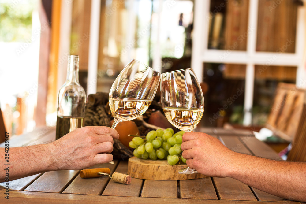 Par de manos brindando con dos copas de vino blanco en una terraza al aire  libre. Vista de frente y de cerca Stock Photo | Adobe Stock