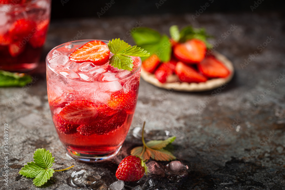 Refreshing summer drink with strawberry slices in glasses on dark background Refreshing summer drink with strawberry slices in glasses on dark background