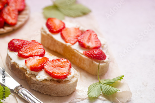 Strawberries sandwiches with cream cheese and on paper, light background