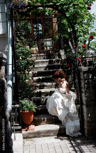 Alone luxury bride wearing stylish wedding white dress waiting in the stairs of the house with flowers © Вероника Зеленина