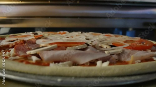closeup of pizza going to hot oven