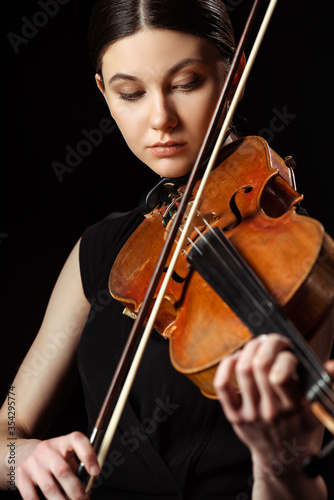 beautiful professional musician playing symphony on violin isolated on black