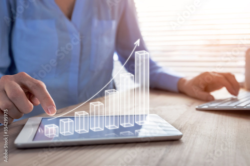 Business success and profit displayed by 3d growing bar chart, successful businesswoman working in bright office with computer and digital tablet, manager increasing revenue photo