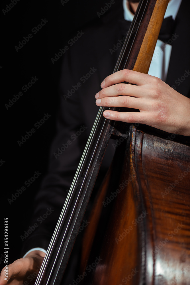 cropped view of male musician playing on contrabass isolated on black cropped view of male musician playing on contrabass isolated on black