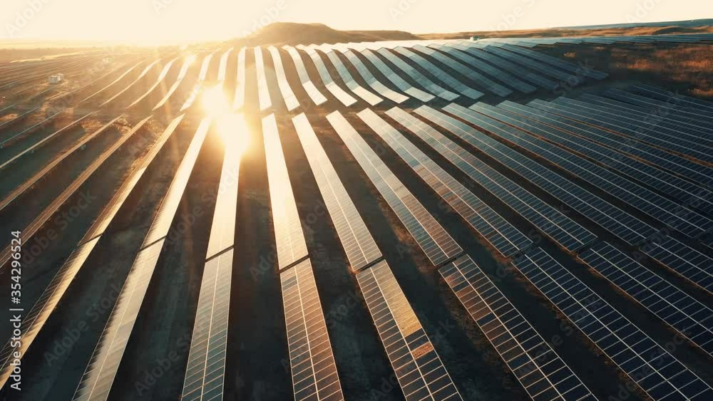 Beautiful aerial view of solar panels stand in a row in the fields green energy at sunset landscape electrical power ecology innovation nature environment slow motion