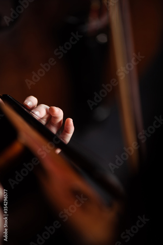 cropped view of professional musician playing on violin on dark stage