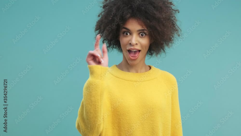 A happy emotional young african american woman with curly hair is ...