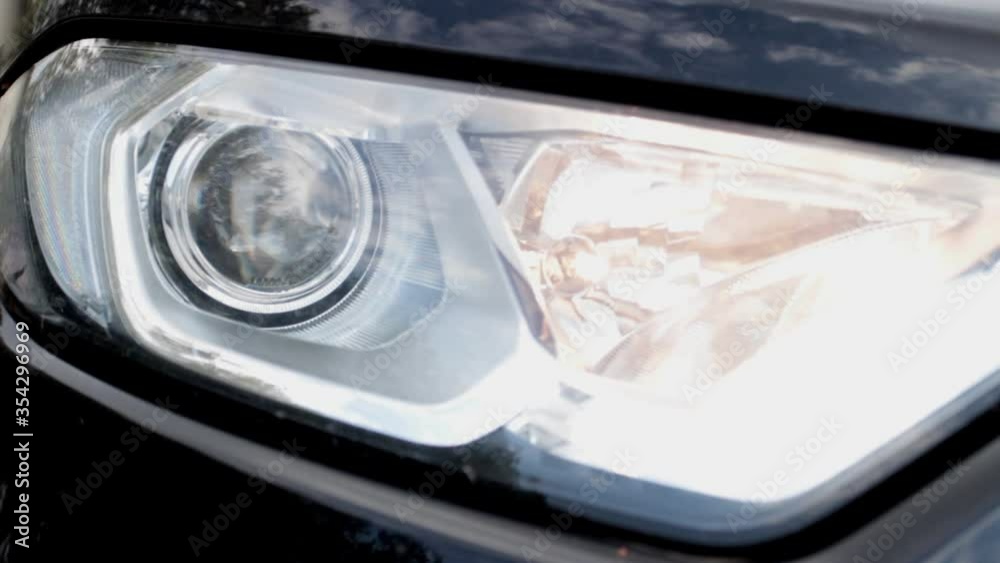 close-up, headlight of a car turns on high beam intermittently