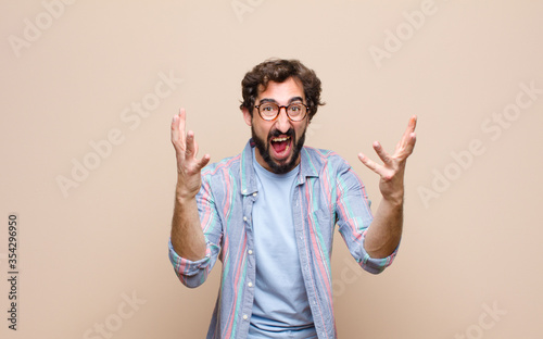 young bearded man against flat wall