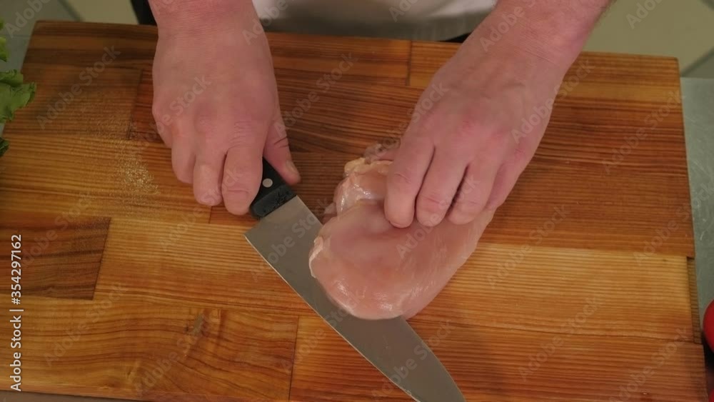 Close-up of a male chef cutting chicken fillets on a cutting Board in the restaurant kitchen. Slow motion. The view from the top. Close-up of a male chef cutting chicken fillets on a cutting Board in the restaurant kitchen. Slow motion. The view from the top.