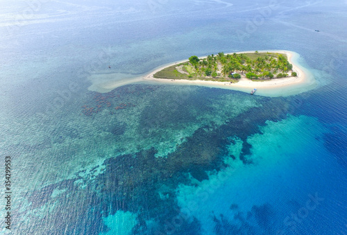 Top view of small isolated tropical island with white sandy beach and blue transparent water