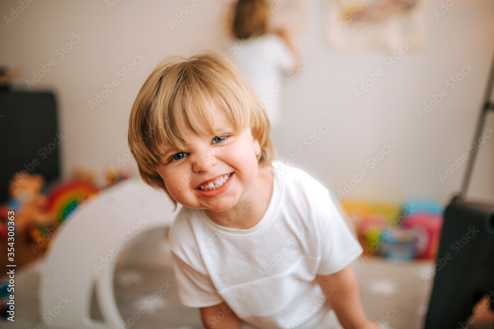 little blond boy laughs looking at camera at home. fun at home family at home little blond boy laughs looking at camera at home. fun at home family at home