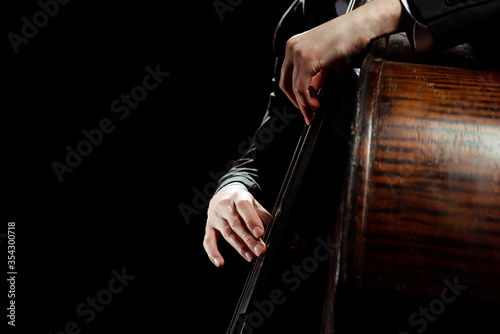 partial view of male professional musician playing on contrabass isolated on black