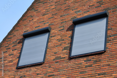Rolling shutters brick house windows protection. Brick house with metal roller shutters on the windows.