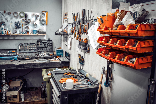Maintenance station, motorcycle and car repair, mechanical equipment on the wall, a set of tools in the workshop. Garage with a large workbench with professional wrenches in drawers and spare parts.