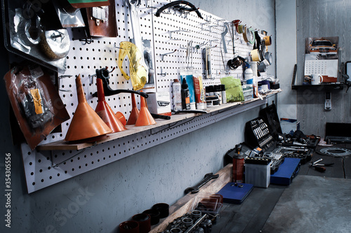 Maintenance station, motorcycle and car repair, mechanical equipment on the wall, a set of tools in the workshop. Garage with a large workbench with professional wrenches in drawers and spare parts.