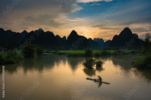 Beautiful silhouette mountains with fisherman and green rice field and river pass at the Phong Nam village in Cao Bang, Vietnam