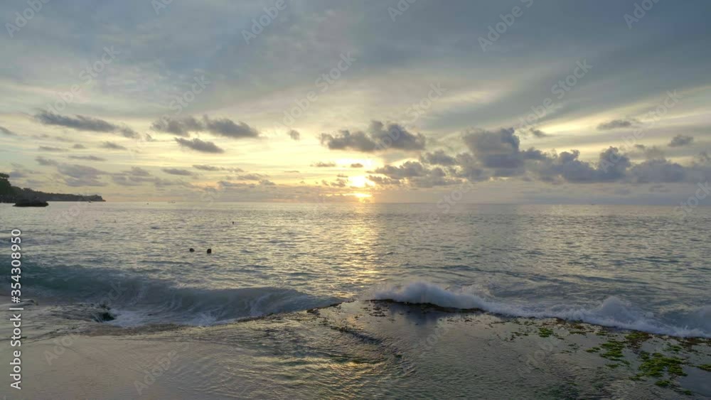 Slow motion of a big tide waves are hitting rock on a beach during beautiful sunset with dark blue sky and yellow sun Slow motion of a big tide waves are hitting rock on a beach during beautiful sunset with dark blue sky and yellow sun
